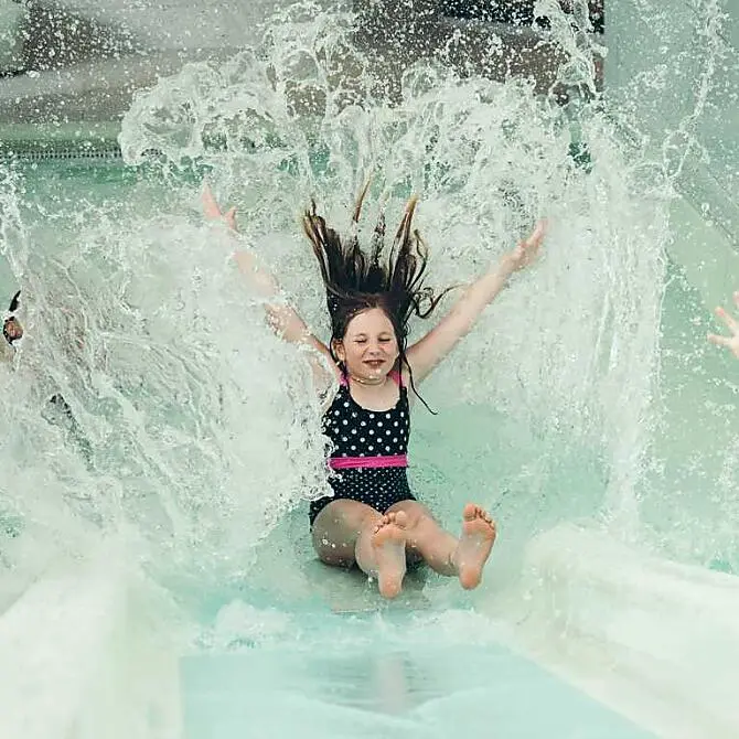 Mädchen rutscht lachen eine der fünf Rutschen in der Wasserwelt im Kinderhotel Ferienwelt Kesselgrub hinunter