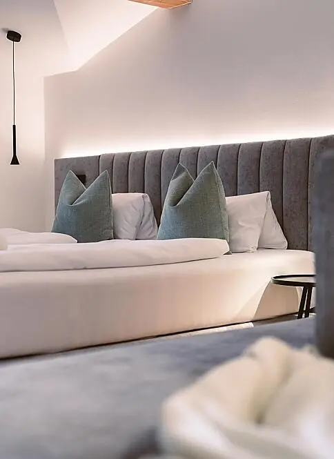 Elegantes Zimmer mit gepolstertem Kopfteil und modernen Pendelleuchten in einem Kinderhotel im Pongau
