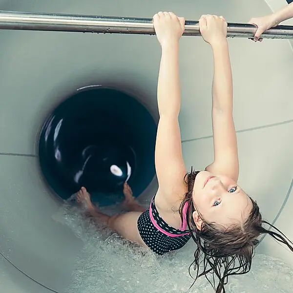 Mädchen rutscht lachend die 90 Meter Wasserrutsche im Kesselgrrub hinunter, Kinderhotel mit 5 Wasserrutschen im Salzburger Land